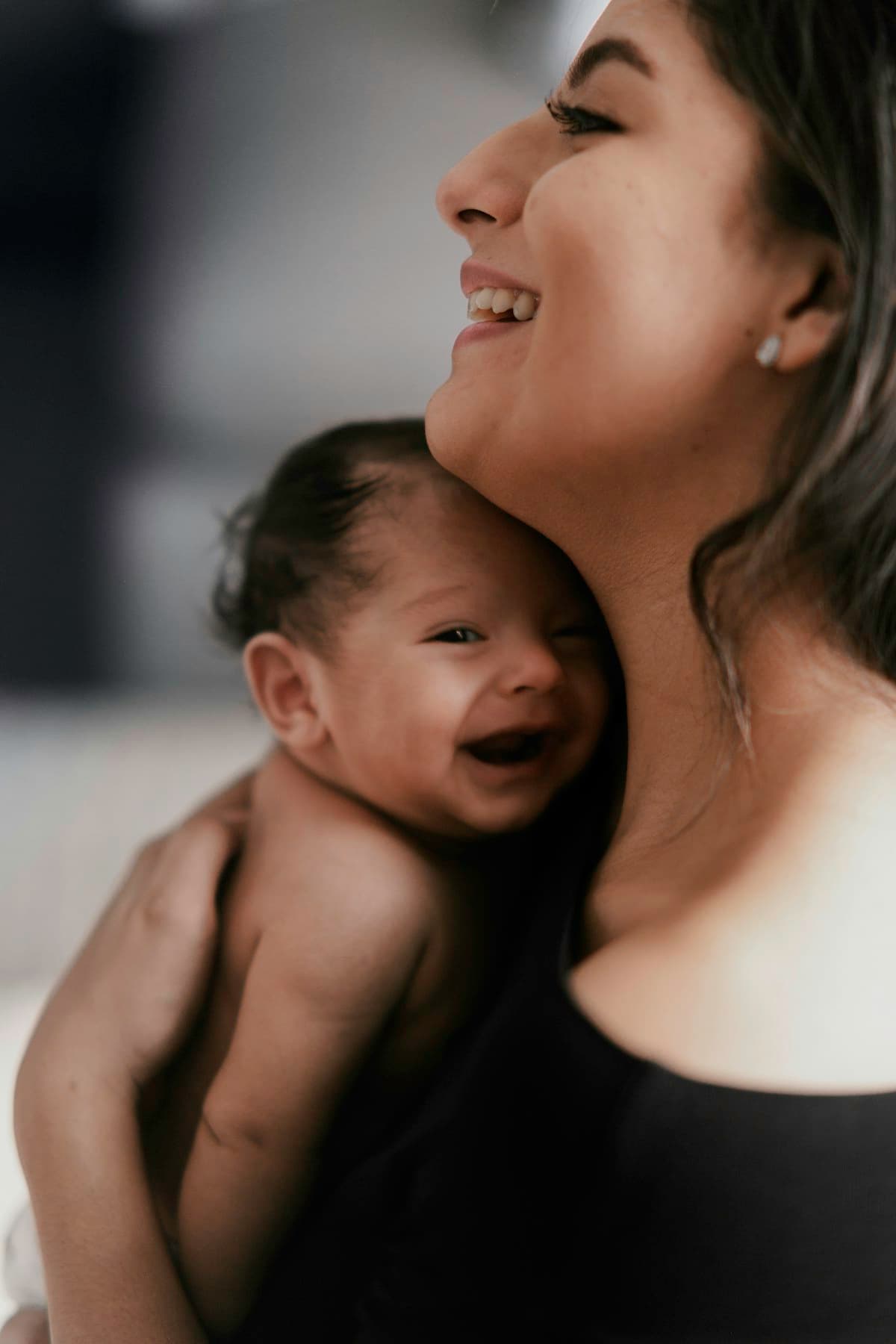 Seorang ibu memeluk bayinya yang tertawa